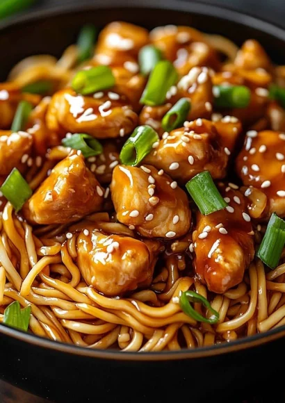 Delicious sticky garlic chicken noodles served in a bowl with fresh herbs